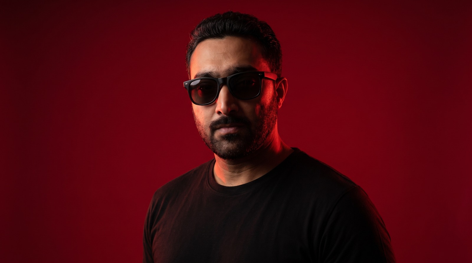 Portrait of Shahrukh Nazar Malik in sunglasses against deep red light