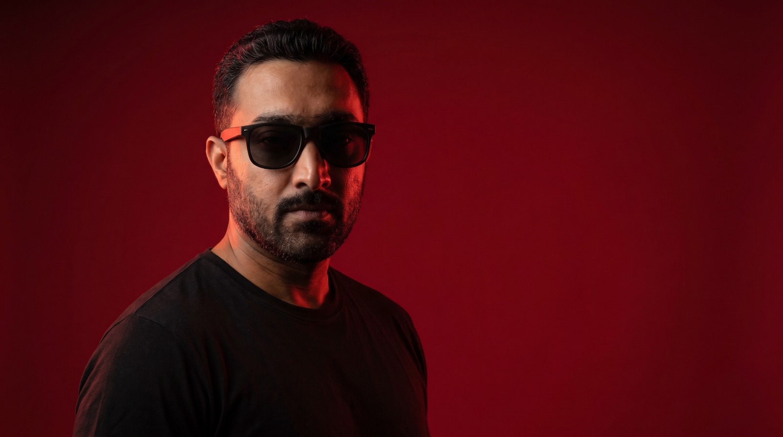Portrait of Shahrukh Nazar Malik against a deep red backdrop